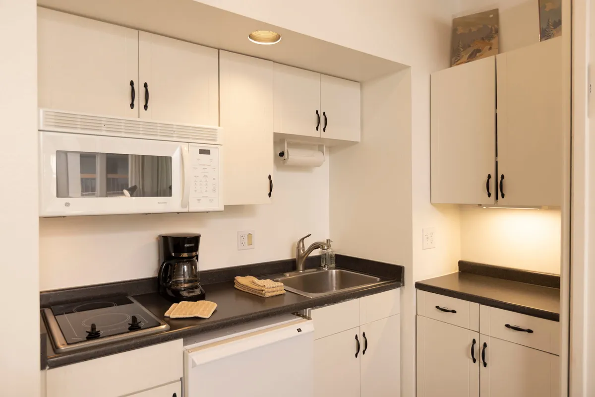 A warm, inviting kitchen space featuring a microwave, coffee maker, sink, and ample countertop. The scene suggests a cozy setting for couples to share morning coffee or prepare meals together in privacy.